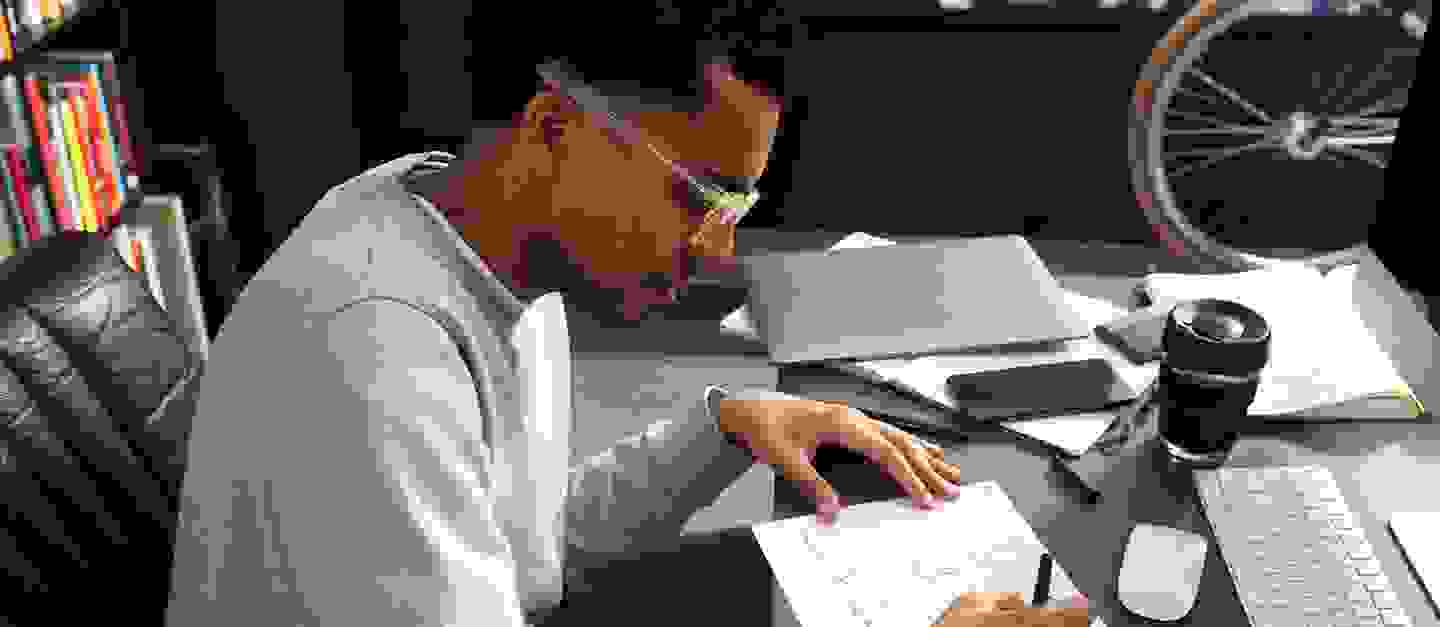 A man sitting at an office desk with a notebook in front of him