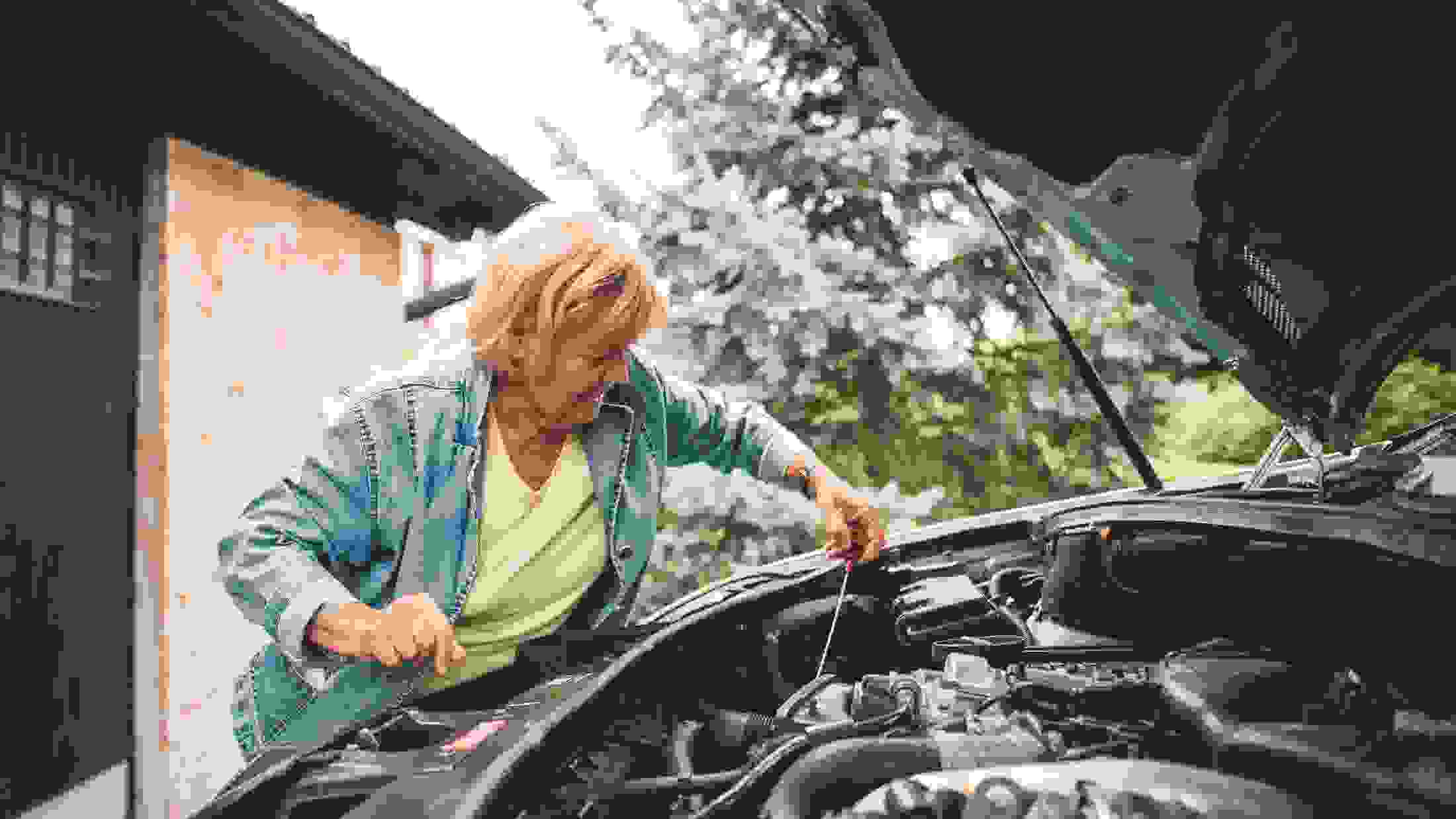 Woman trying to repair a broken down car