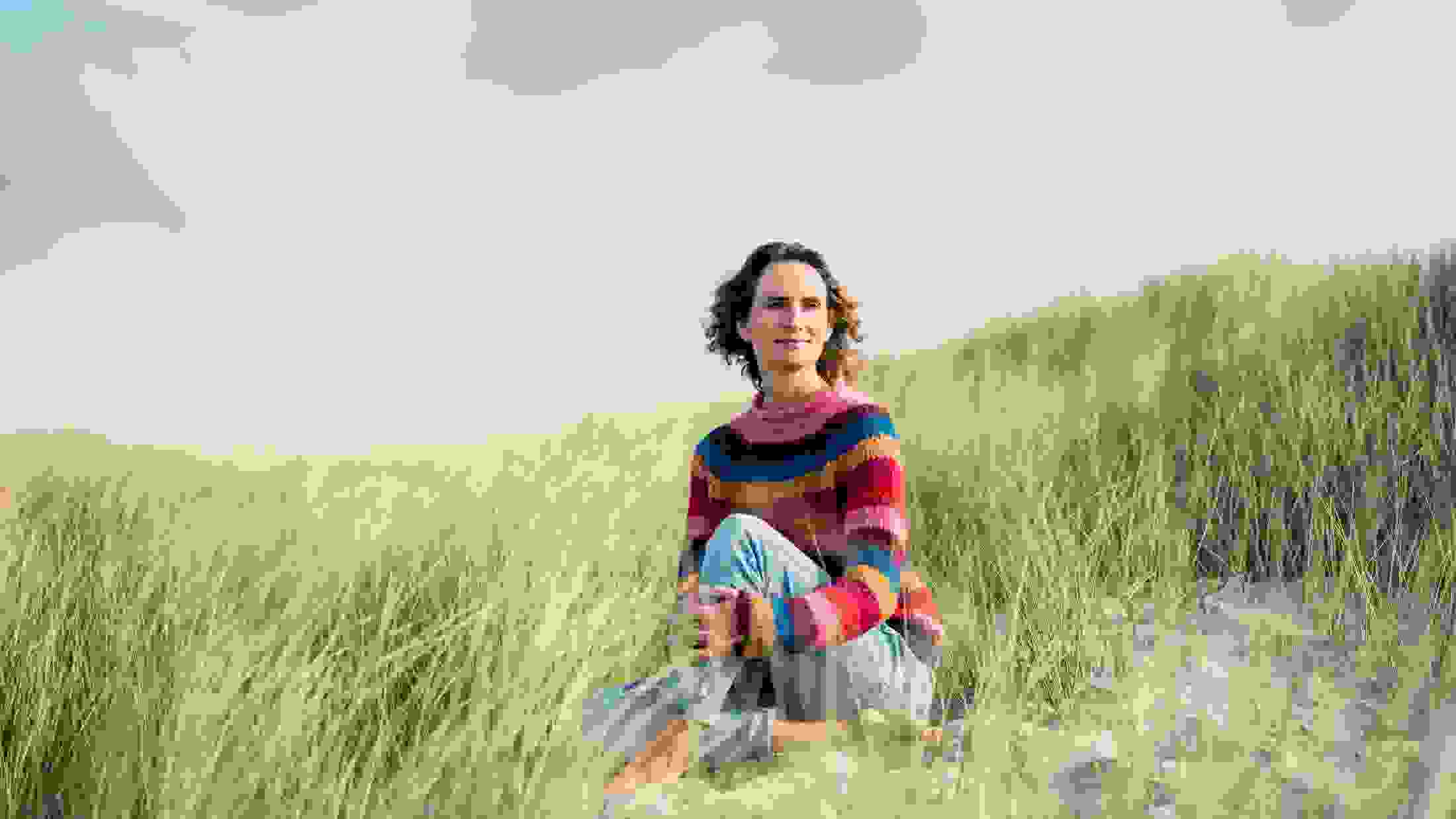 Mature woman relaxing on the beach, sitting in the dunes