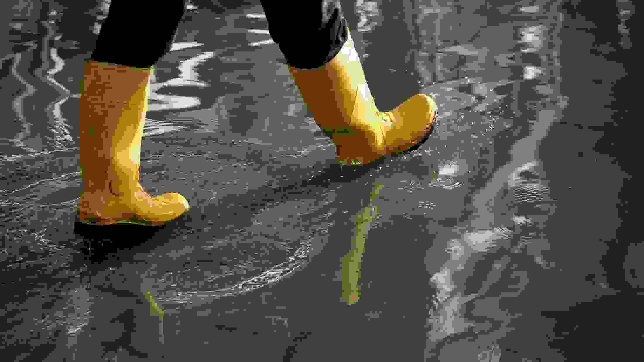 Walking in a flood masthead with a pair of yellow waterproof boot 