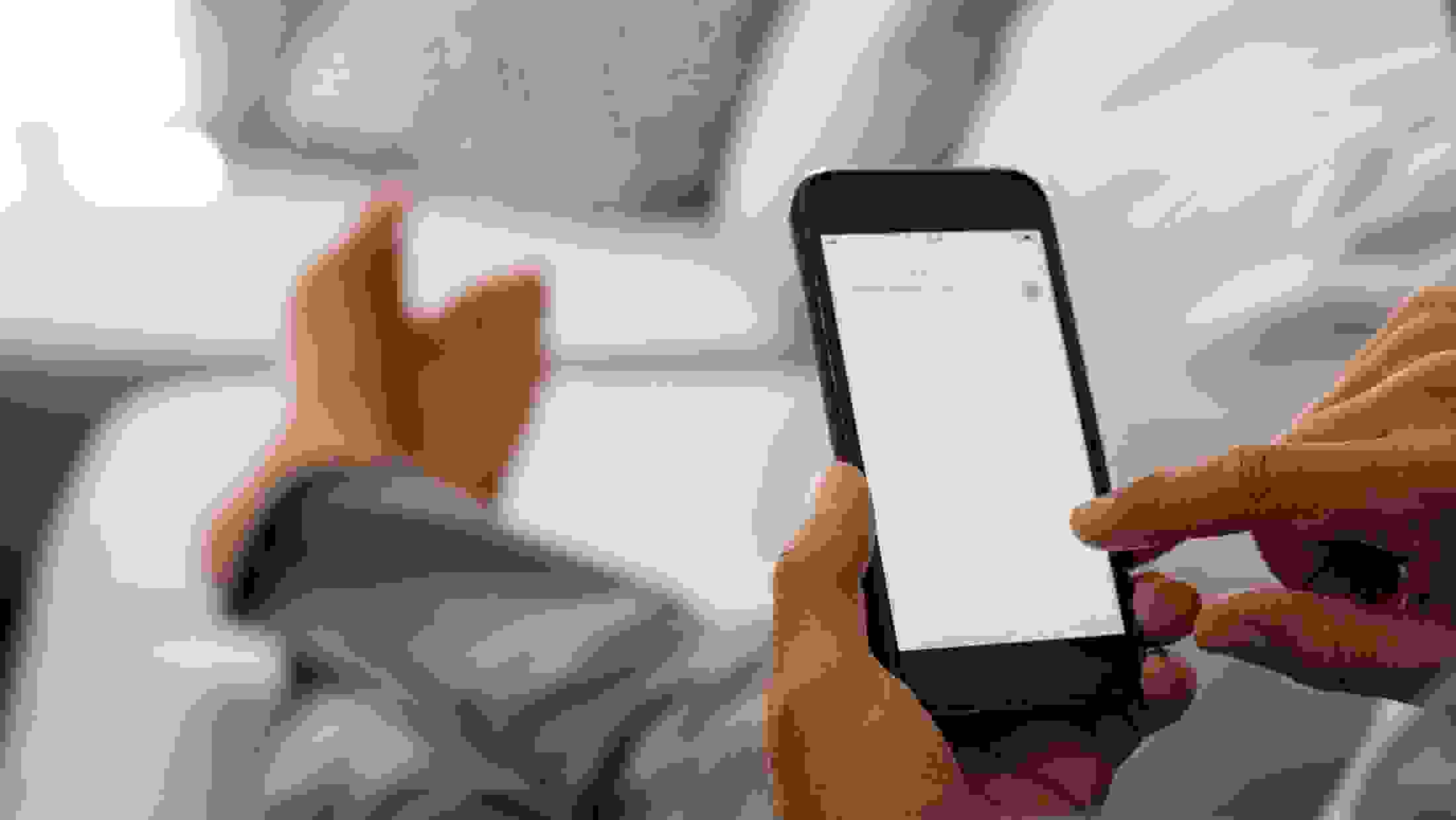Closeup of a person holding a mobile phone while reading a document on the screen
