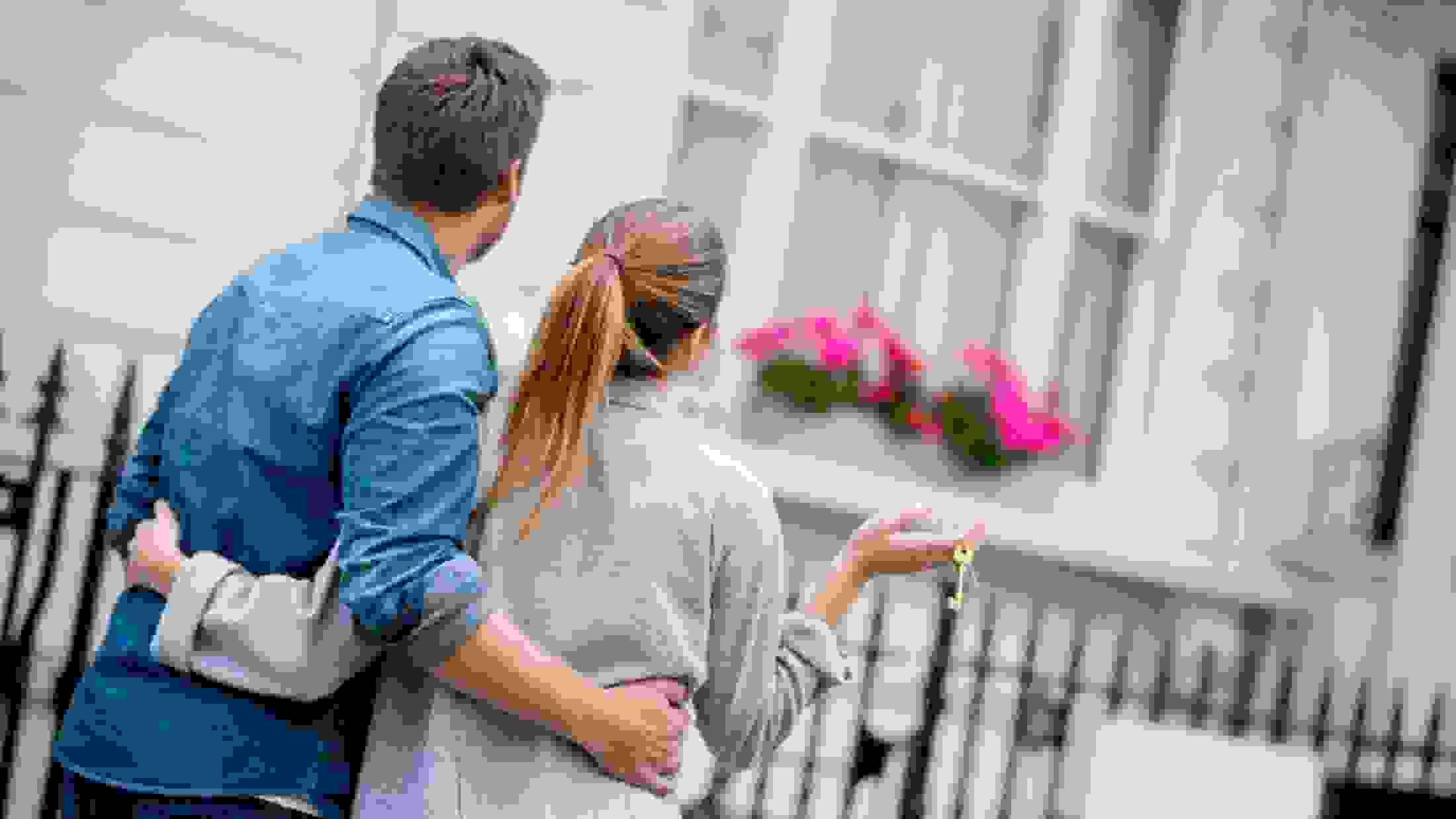 Young couple walking with arms round each other, and woman holding a set of keys
