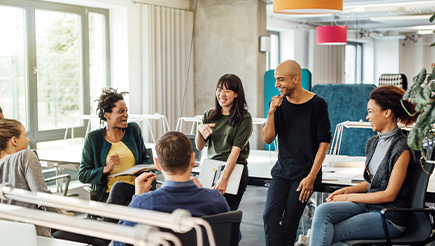 A group of coworkers sitting in a circle at an office - talking and laughing