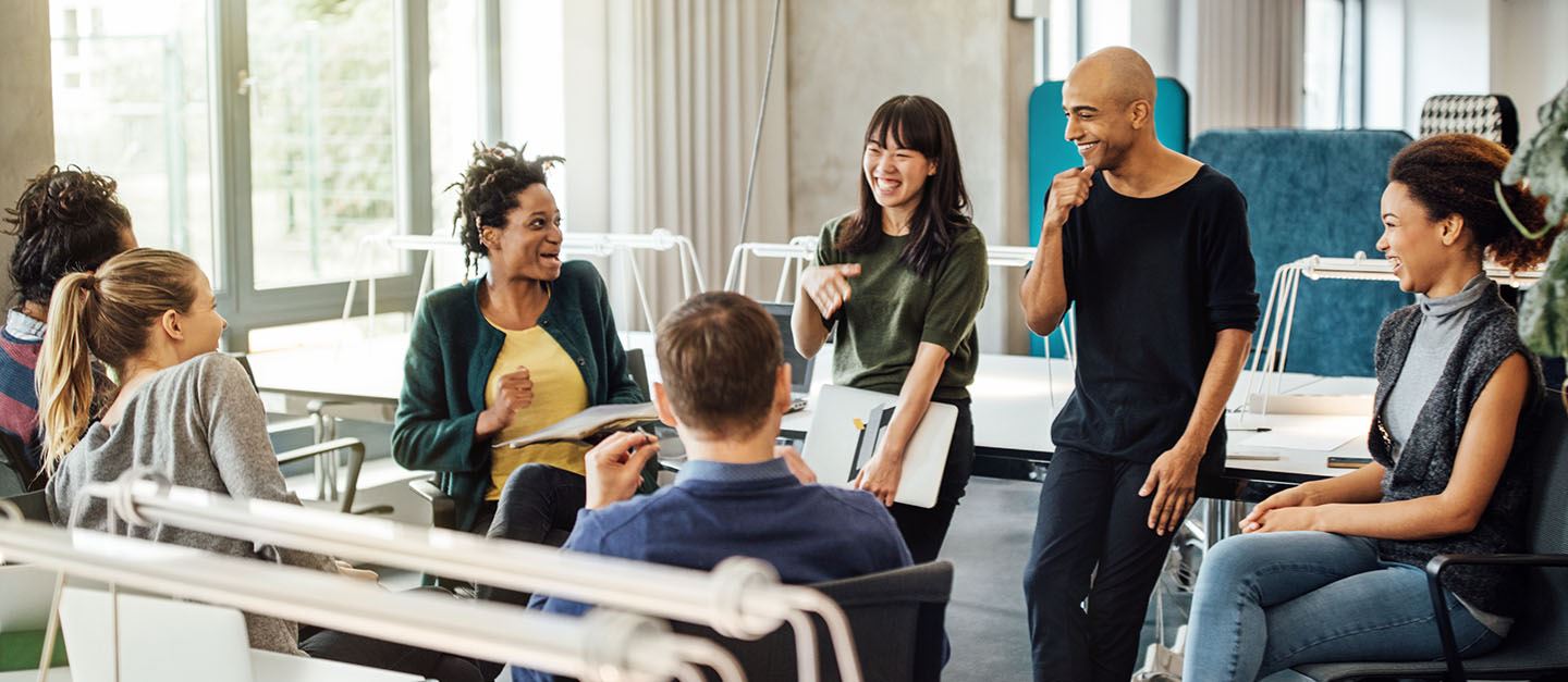 A group of coworkers sitting in a circle at an office - talking and laughing