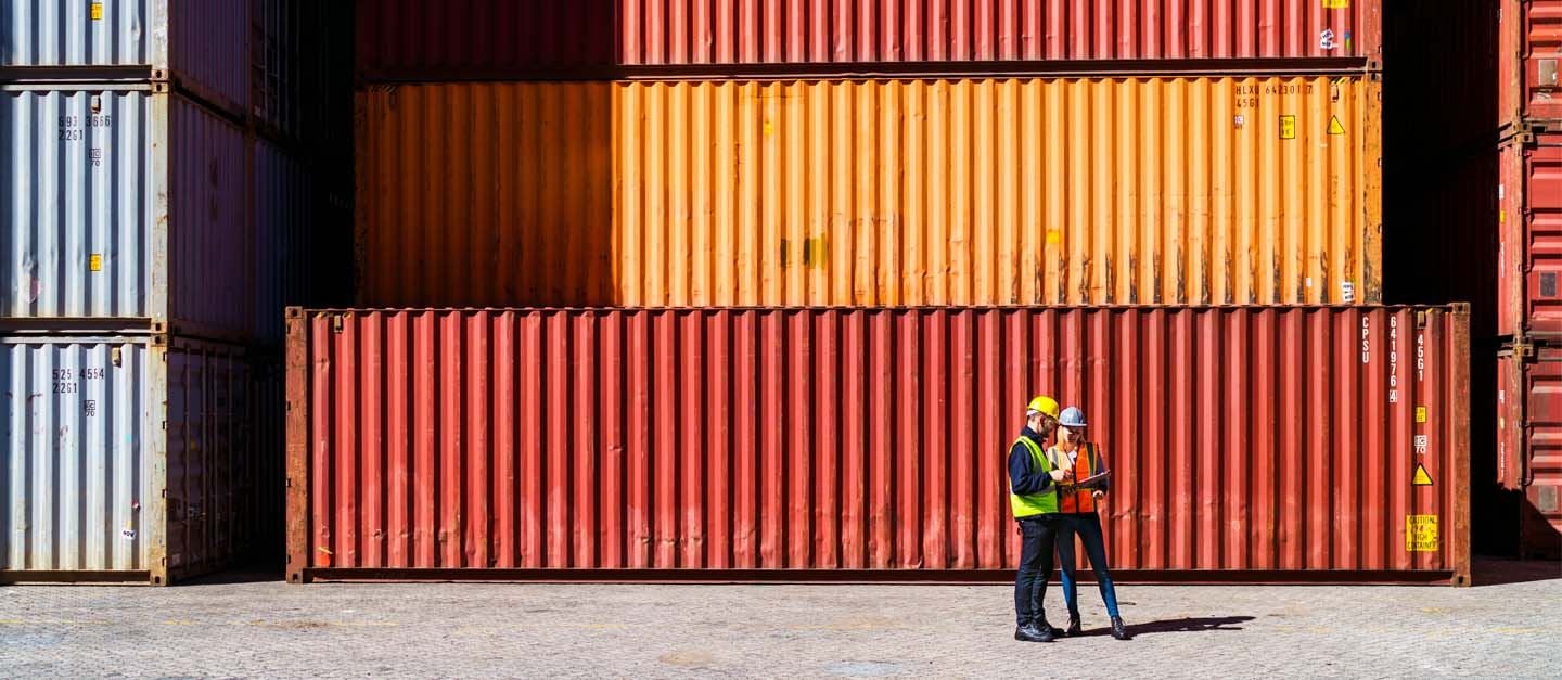 A worker standing in front of colourful shipping containers.