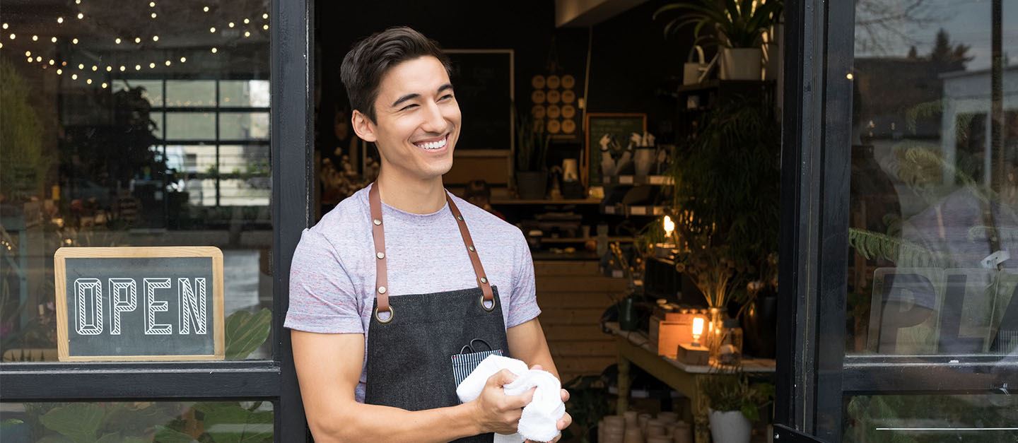 A cafe owner standing outside their shop