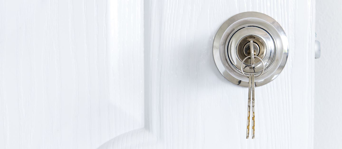 A white door with a key hanging from the lock