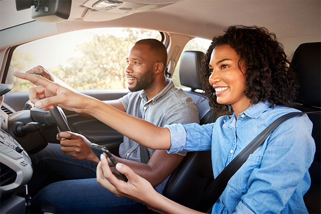 Man driving with woman using phone for directions