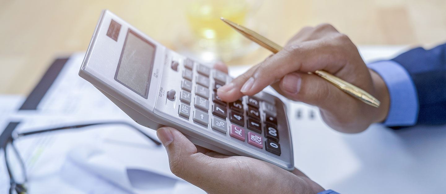 A hand holding their calculator and looking at business expenses