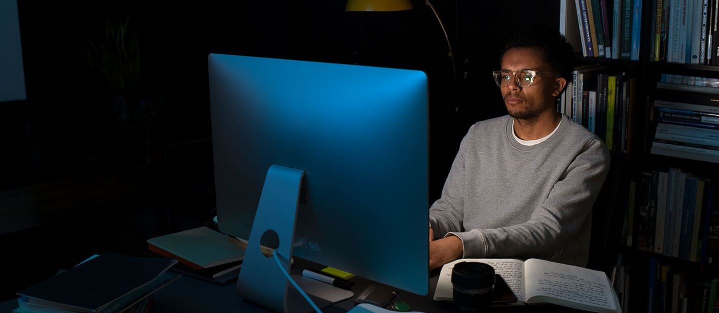 A man sitting in the dark looking at his computer screen