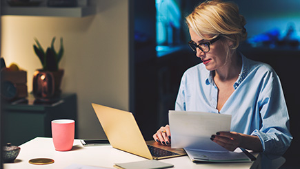 A woman sitting at a table covered in paperwork
