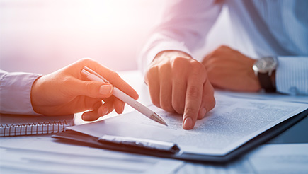 Hands resting over a piece of paperwork as the fill it out.
