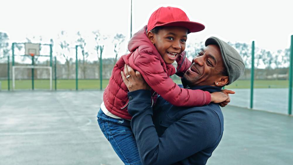 Black grandfather holding his grandchild in a play area