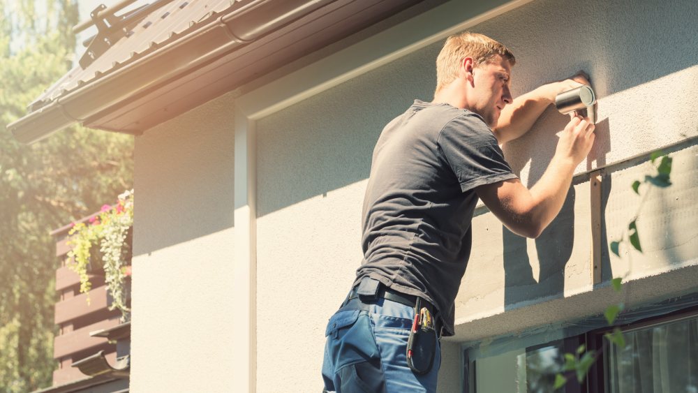 Man fitting a security camera to property