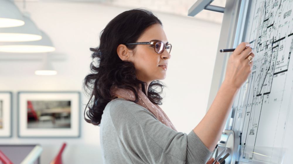 Woman standing up making notes on architectural plans