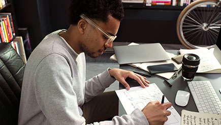 A man at his office desk writing in a notebook
