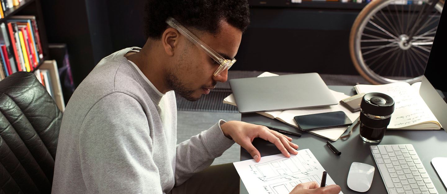 A man sitting at an office desk with a notebook in front of him