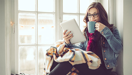 A person holding an iPad and a coffee