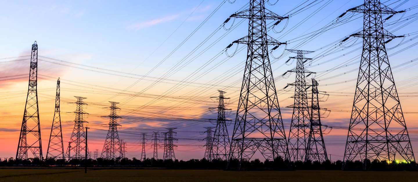 A set of tall powerlines against a sunset