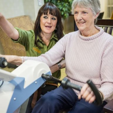 Dementia sufferer Anne sat on Motiview bicycle with care worker Zoe by her side