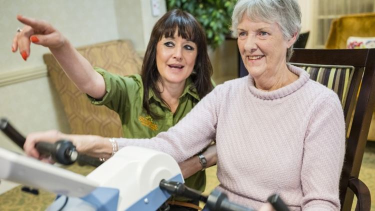 Dementia sufferer Anne sat on Motiview bicycle with care worker Zoe by her side