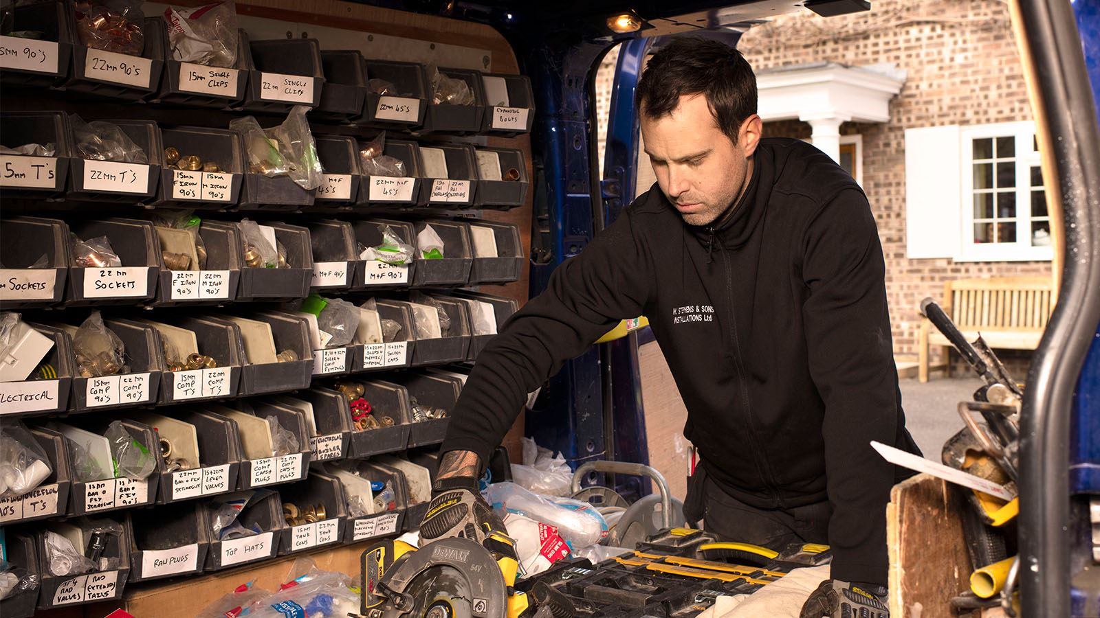 Tradesman looking in his van for equipment