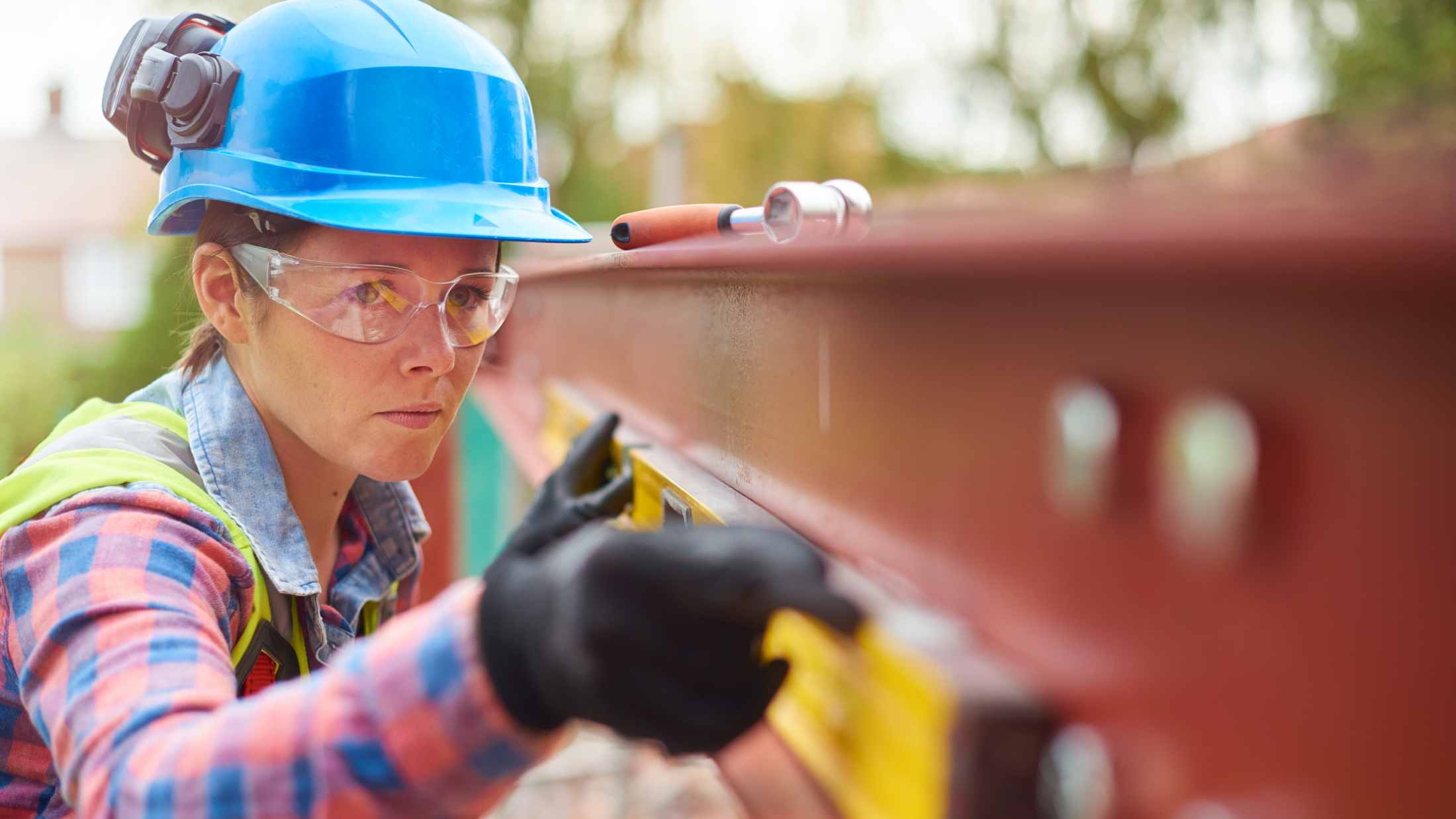 A young female steel erector marks off steel where she is about to drill