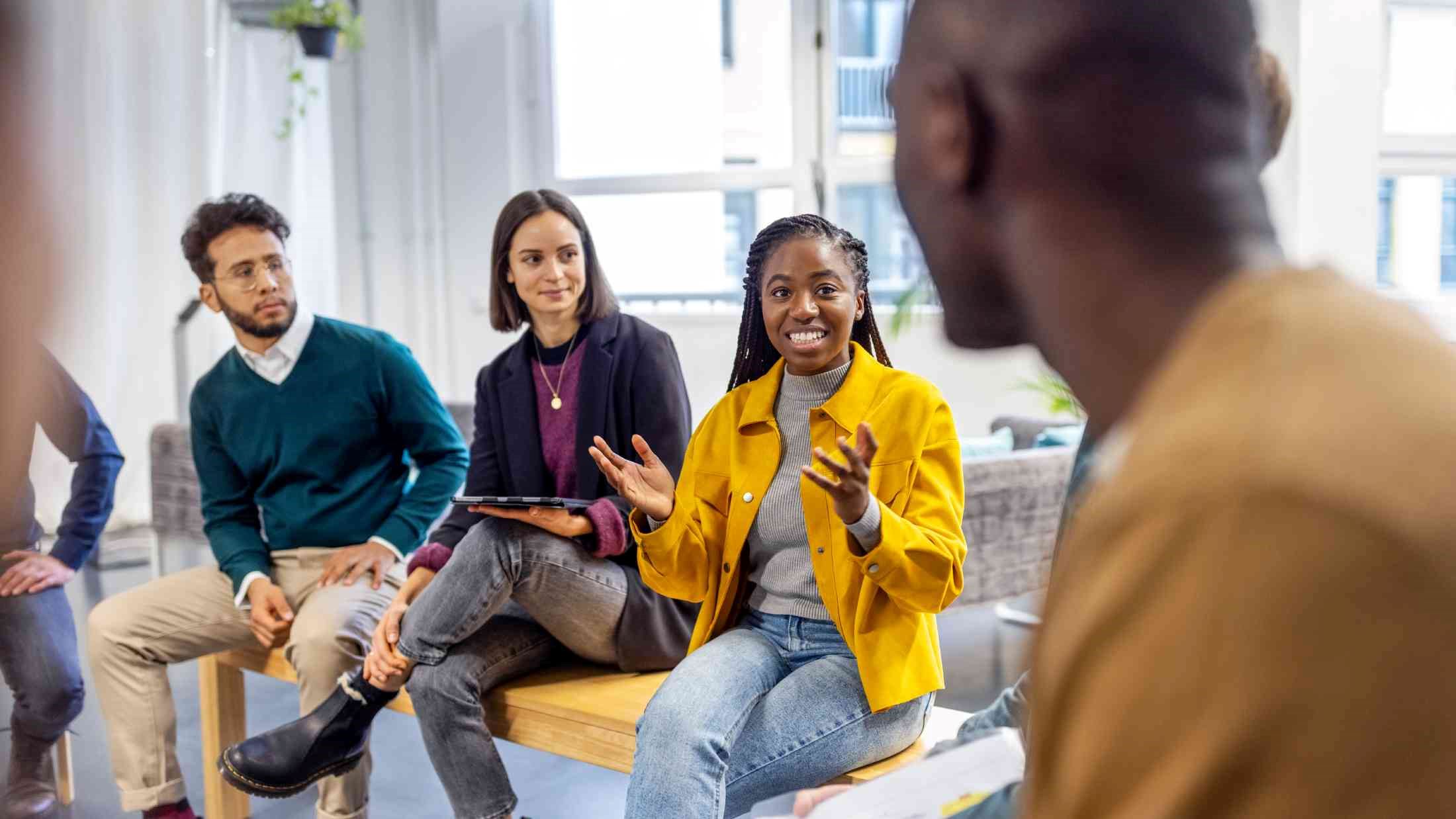 African woman talking with colleagues sitting in circle at a coworking office