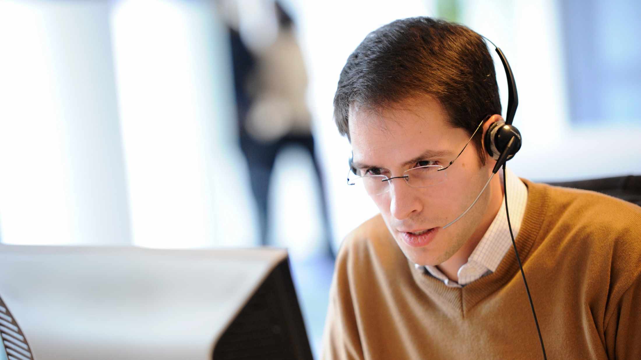 AXA employee sat at computer screen while wearing a headset