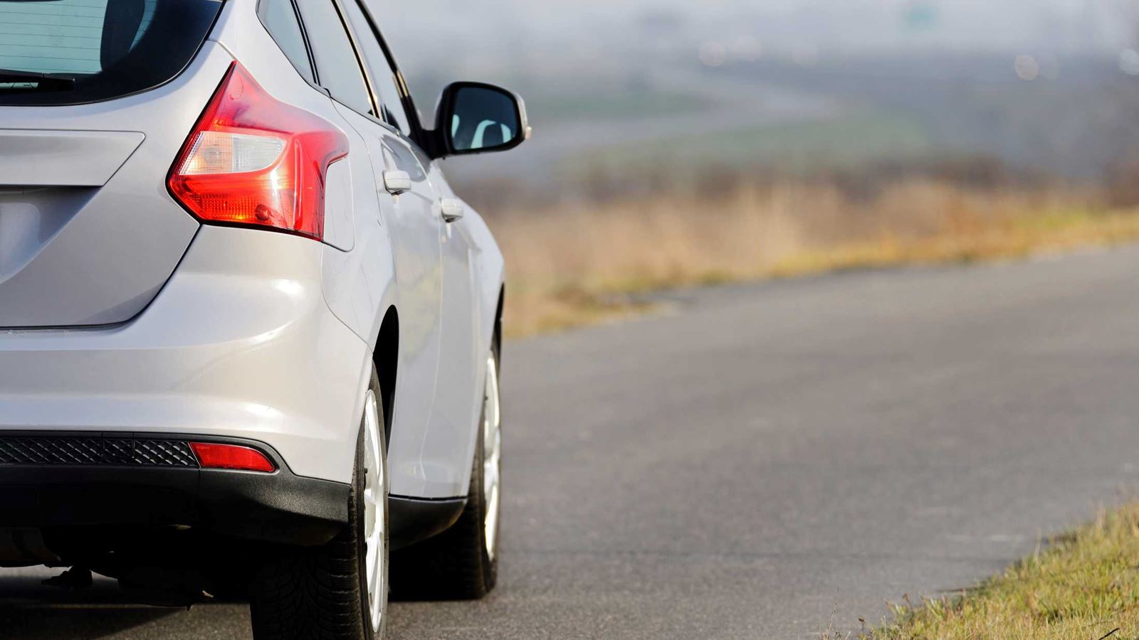 Grey hatchback car driving down a road