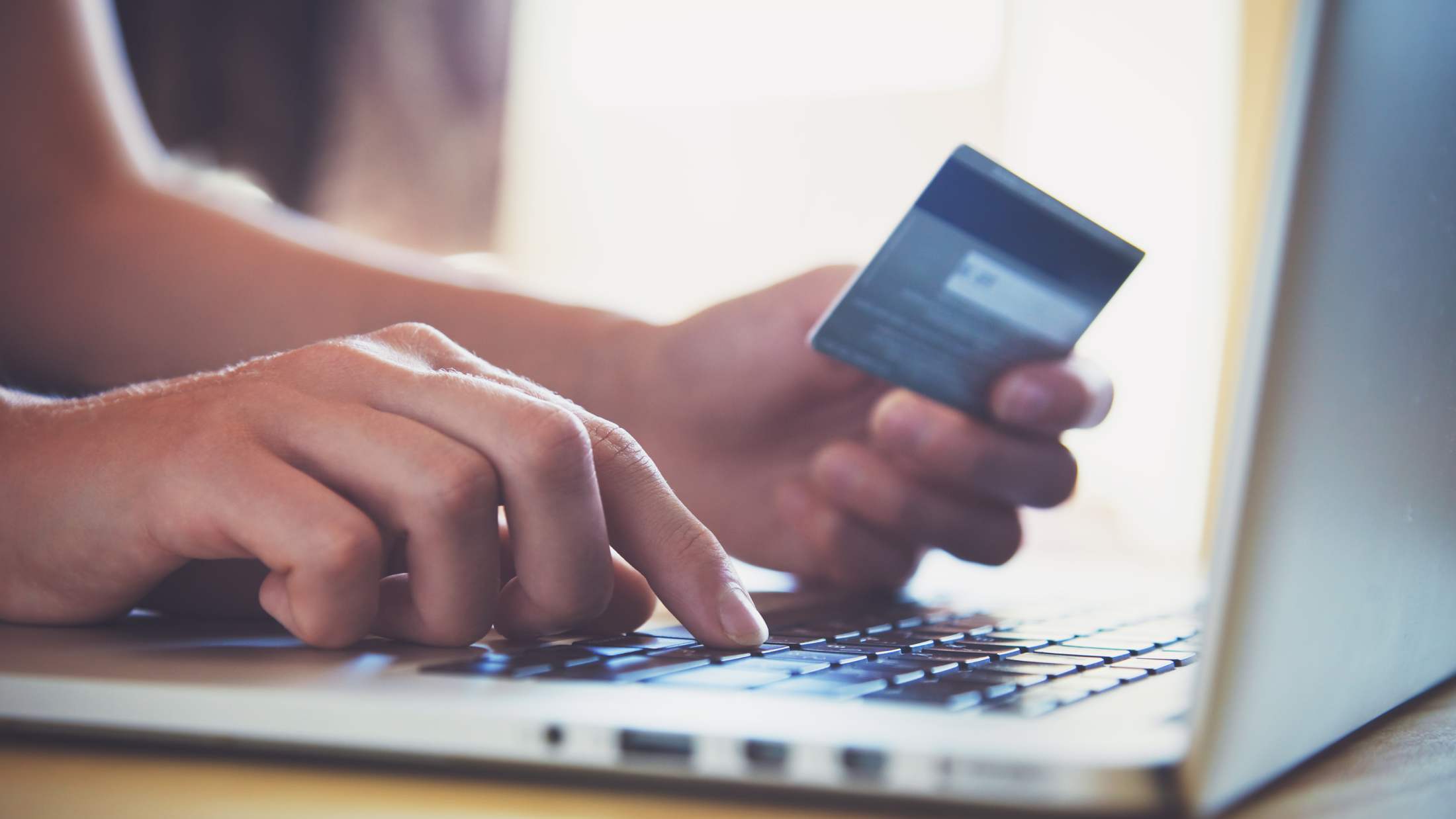 Hands holding credit card and using laptop