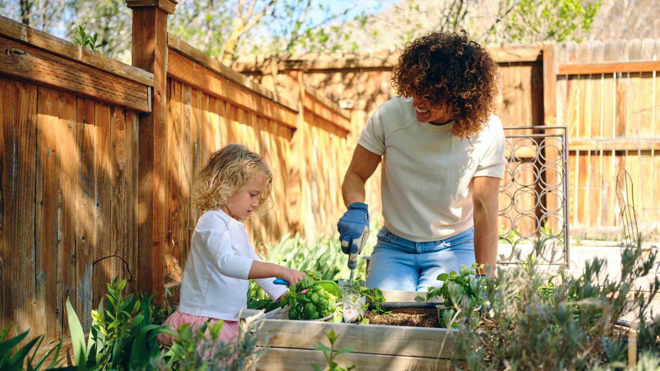 Mother and young daughter in garden planting herbs together