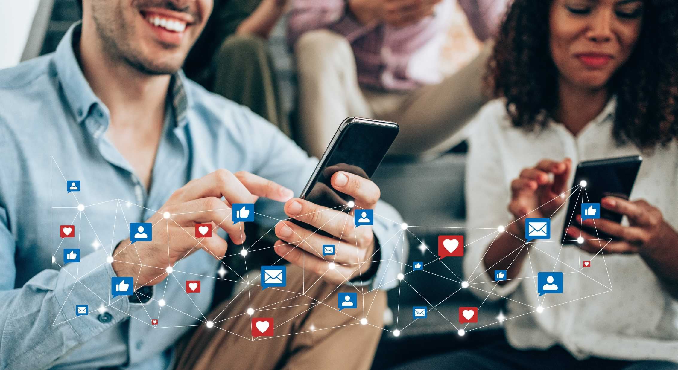 Multi-ethnic group of young people sitting on stairs and using smartphones. Young smiling man receives notifications on smart phone. Social media and digital online concept. Social media and people network technology concept.