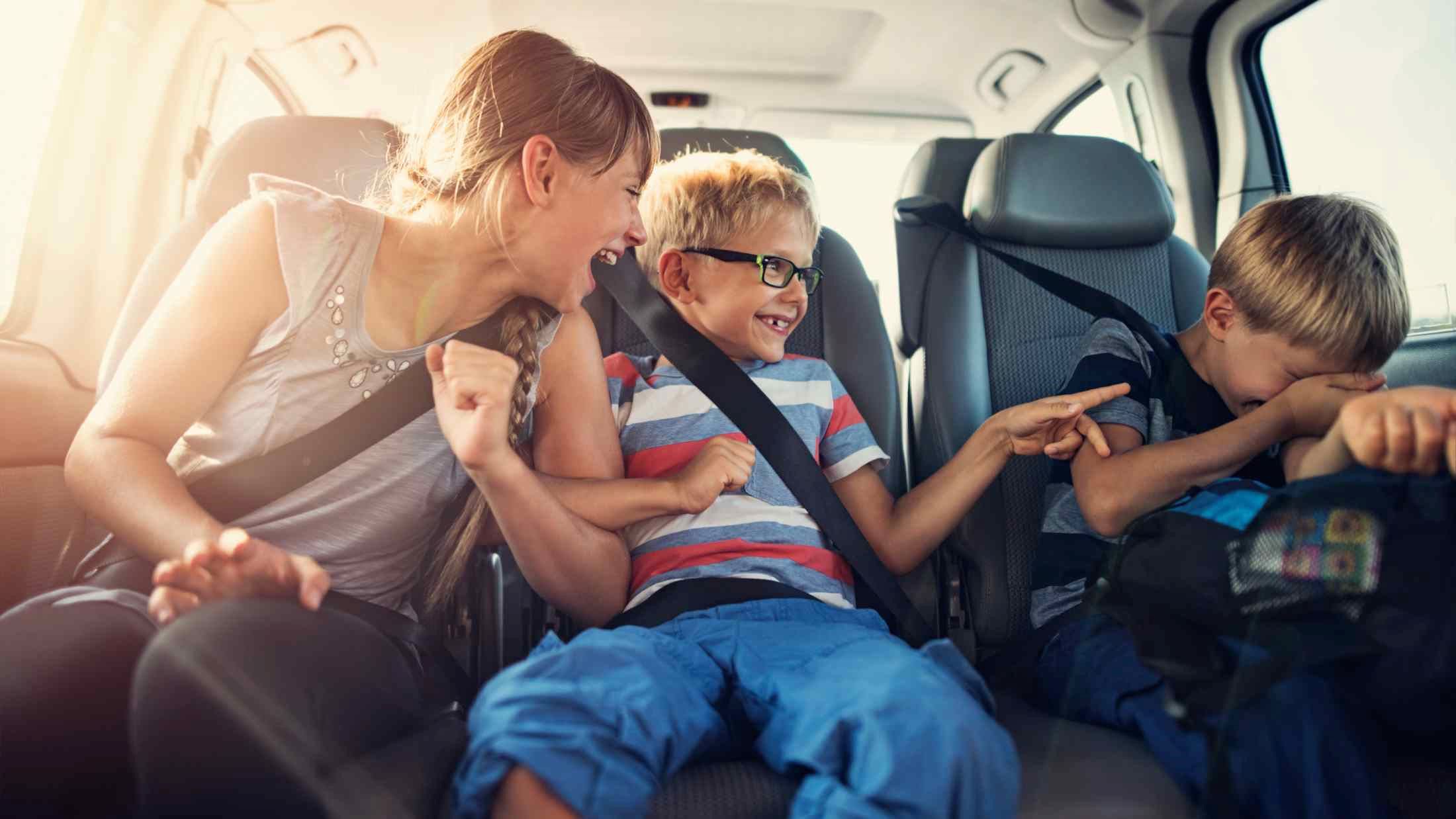 Three kids aged between 8 and 11 laughing in the back of a car