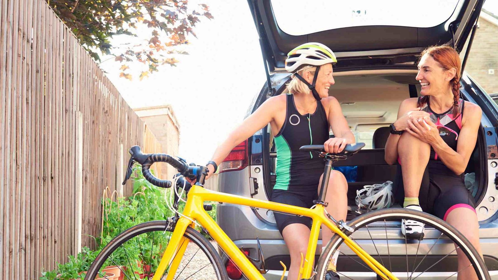 Two mature women sitting in car with racing bicycle