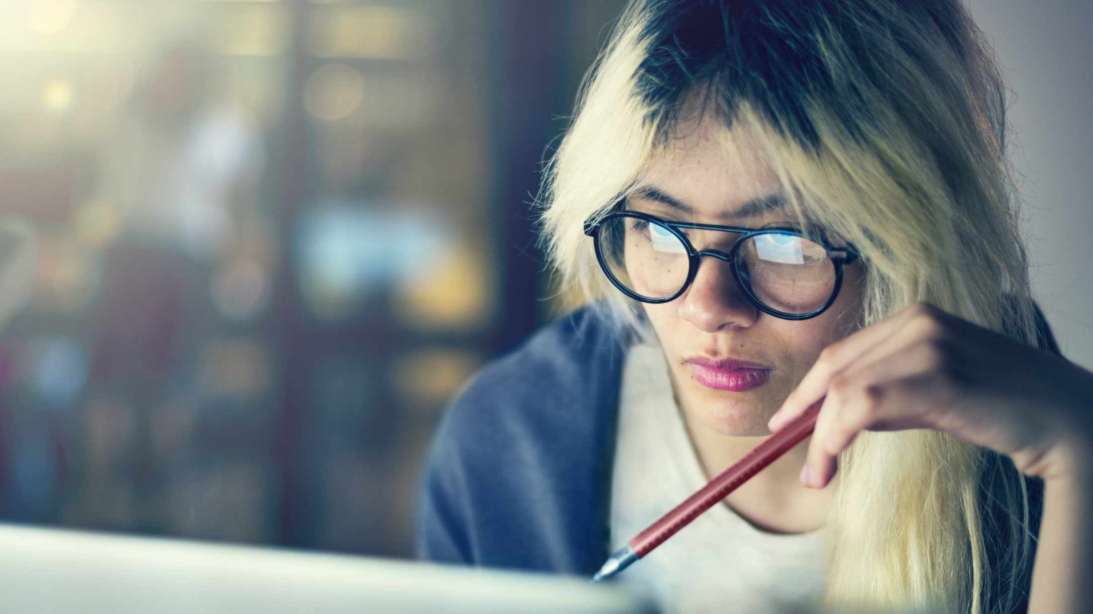 Woman with a pen working on a laptop