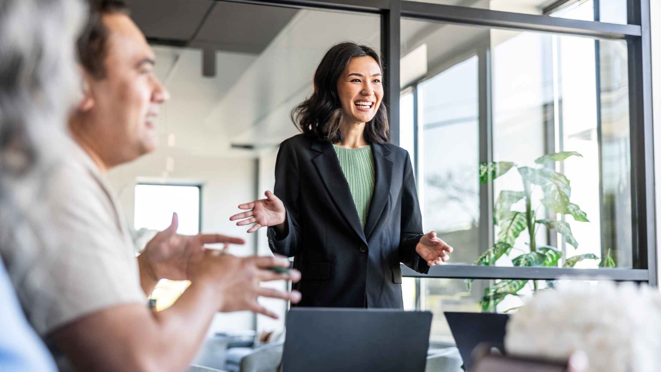 Young businesswoman speaking to colleagues in modern conference room