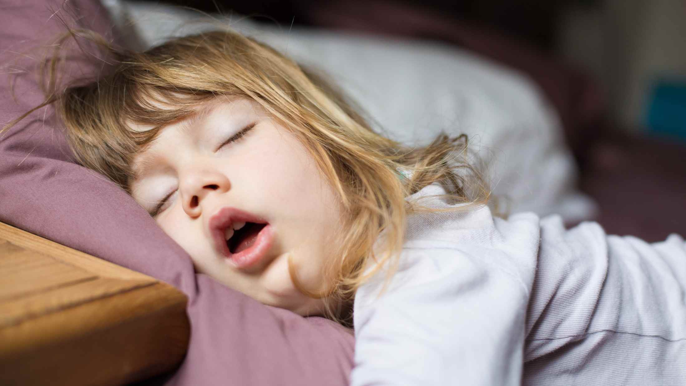 Young girl asleep on a purple pillow
