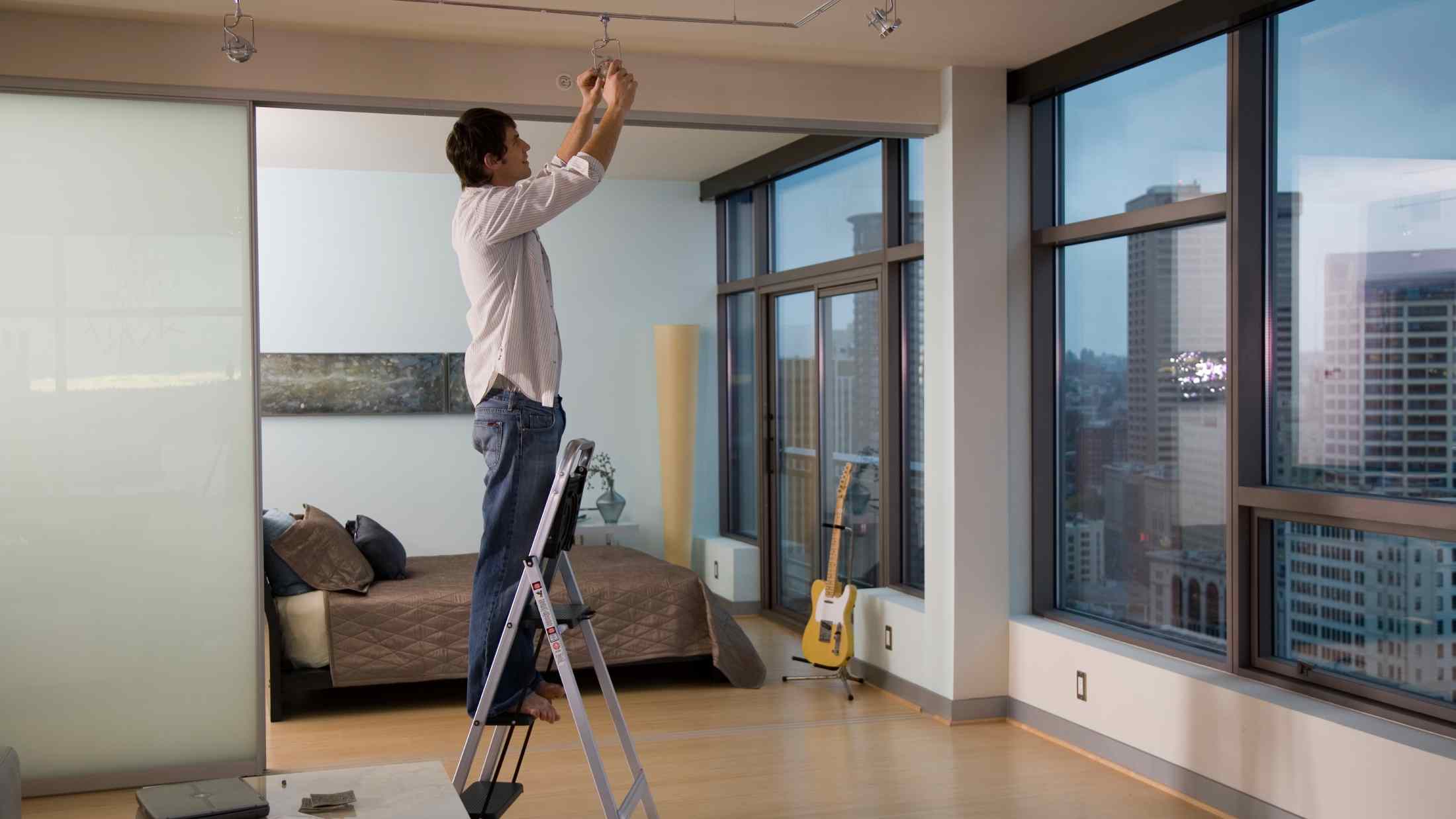 Young man replacing light bulb