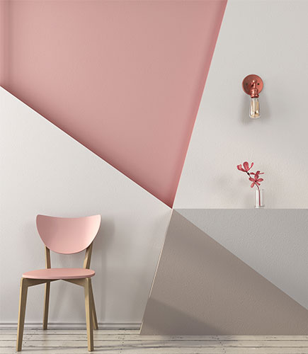 Wall design featuring white, pink and grey geometric shapes anda pink coloured chair