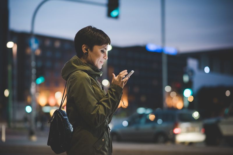 Woman wearing earphones holding her phone
