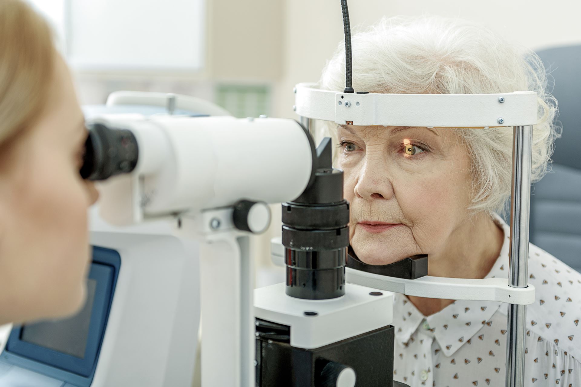 an senior woman checking her eyes with an opticians