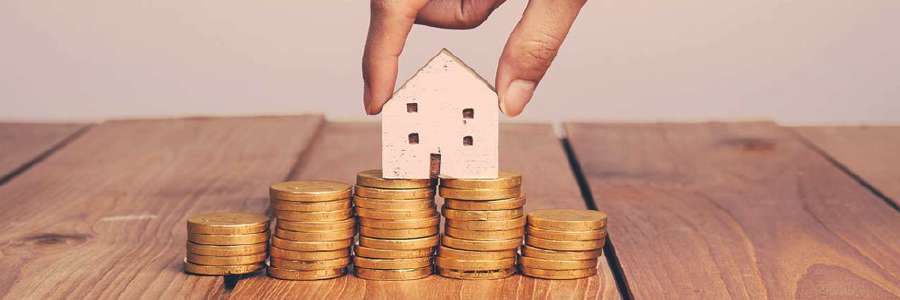 Paper house balancing on coins