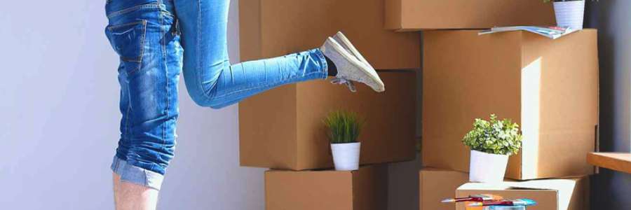 Woman wearing jeans with one leg raised with packing boxes in background