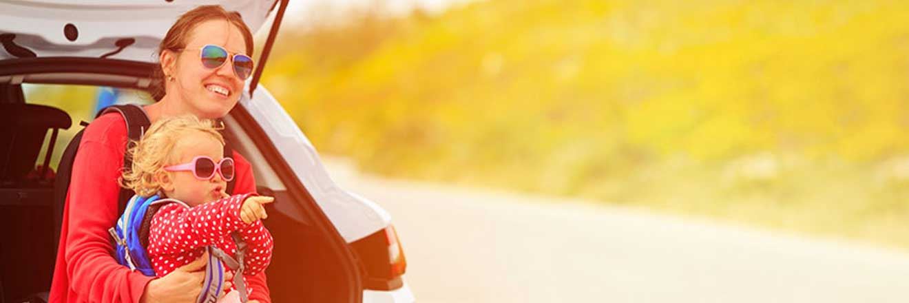 A mother and child sitting on the trunk of their car