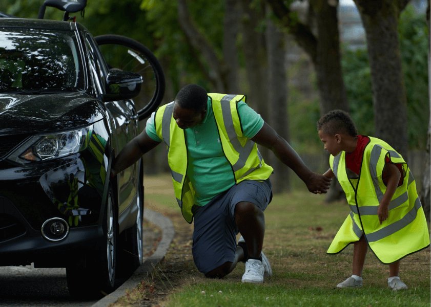 Father and son wearning hi-vis jackets checking their car's tyres