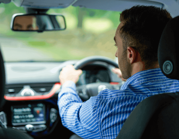 Man driving a car as viewed from rear passenger seats