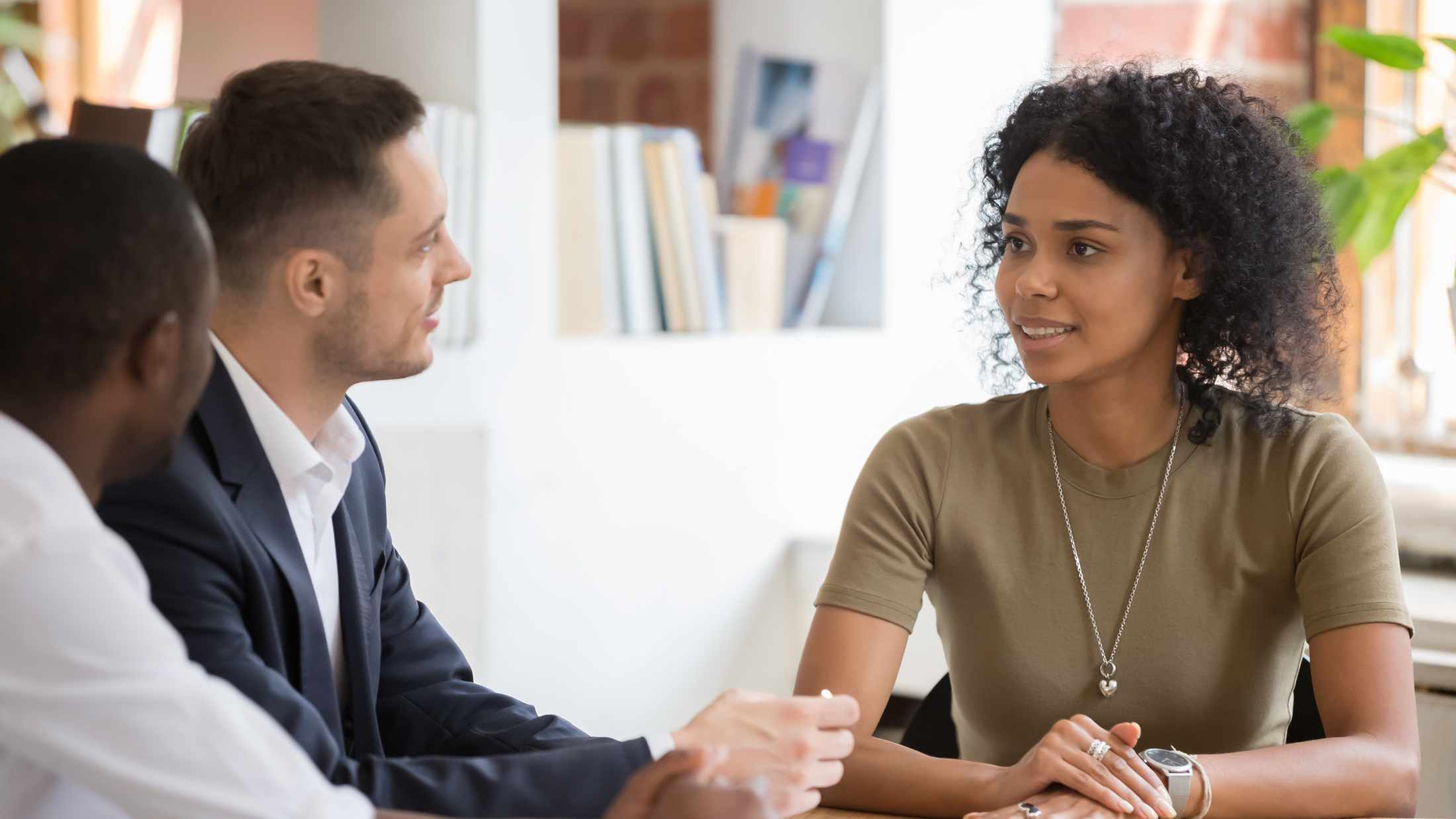 Confident African black female applicant talking to diverse hr managers recruiters at job interview