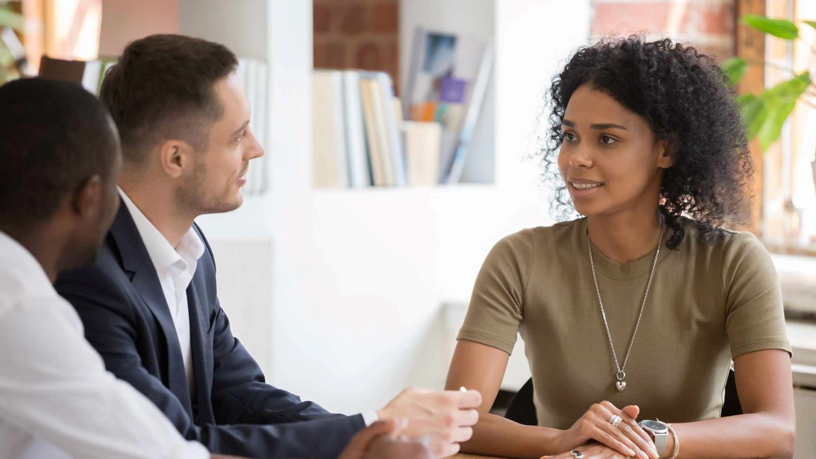 Confident African black female applicant talking to diverse hr managers recruiters at job interview