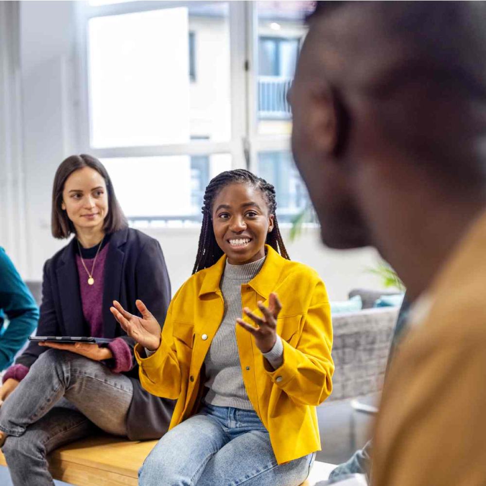 African woman talking with colleagues sitting in circle at a coworking office